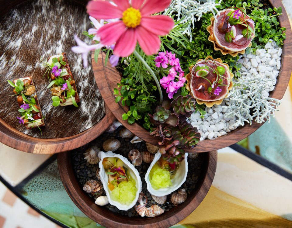 Ett potpourri av färgglada maträtter serverade i en träkonstruktion som rullas ut till gästen. I centrum en rosa blomma. På La Petite Colombe, en av de bästa restaurangerna i Franschhoek, får både ögat och gommen sitt.