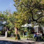 Stellenbosch dining and ambience a small restaurant near a road with green signs and people eating outside on a sunny day.