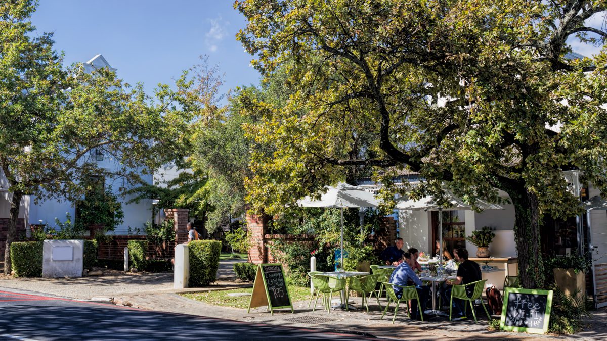 Stellenbosch dining and ambience a small restaurant near a road with green signs and people eating outside on a sunny day.