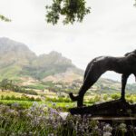 En staty på vingården Delaire Graff med blommor i förgrunden och berg i bakgrunden. En slående vy från en av de bästa restaurangerna i Stellenbosch.
